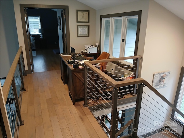 hall featuring a healthy amount of sunlight, lofted ceiling, and light wood-type flooring