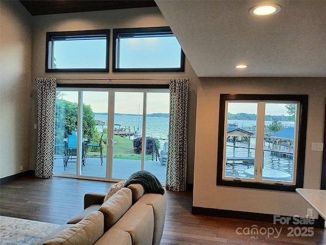 living room with recessed lighting, hardwood / wood-style floors, a water view, and baseboards