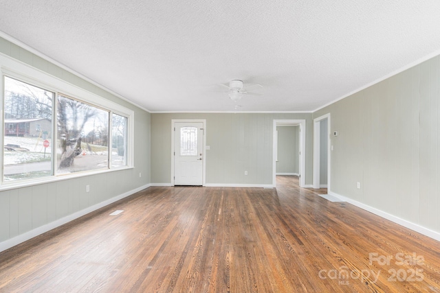 empty room with dark hardwood / wood-style flooring, crown molding, a textured ceiling, and ceiling fan