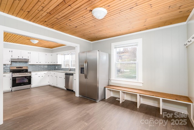 kitchen featuring appliances with stainless steel finishes, ornamental molding, white cabinets, decorative backsplash, and wooden ceiling