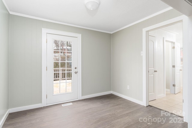 empty room with ornamental molding, a healthy amount of sunlight, a textured ceiling, and light wood-type flooring