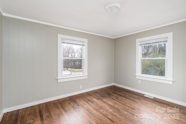 empty room with crown molding, a healthy amount of sunlight, and dark hardwood / wood-style floors