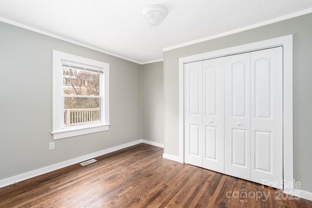 unfurnished bedroom with ornamental molding, dark hardwood / wood-style floors, and a closet