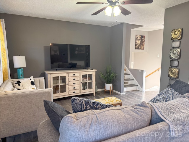 living room with ceiling fan, wood-type flooring, and a textured ceiling