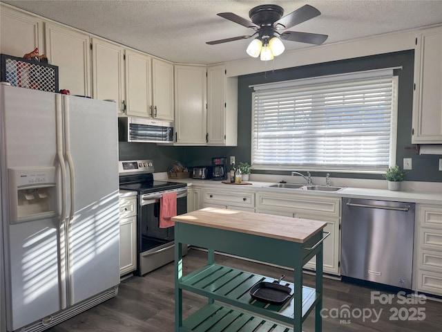 kitchen with white cabinets, appliances with stainless steel finishes, dark hardwood / wood-style flooring, sink, and ceiling fan