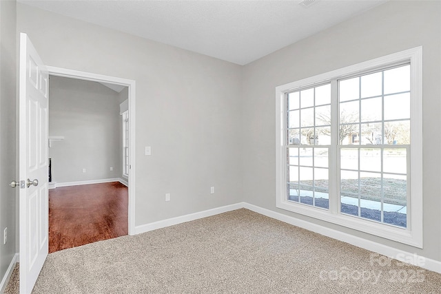 spare room featuring baseboards, dark carpet, and a textured ceiling