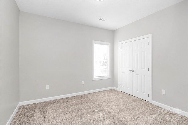 unfurnished bedroom featuring carpet, visible vents, baseboards, and a closet