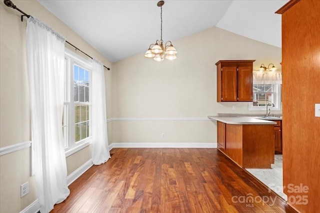 kitchen featuring kitchen peninsula, sink, dark wood-type flooring, and vaulted ceiling