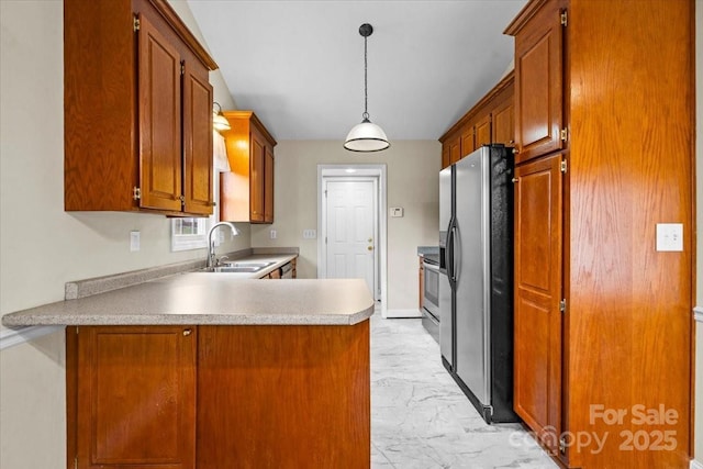 kitchen with kitchen peninsula, sink, pendant lighting, and stainless steel refrigerator with ice dispenser