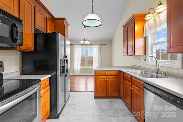 kitchen with sink, a notable chandelier, kitchen peninsula, decorative light fixtures, and appliances with stainless steel finishes