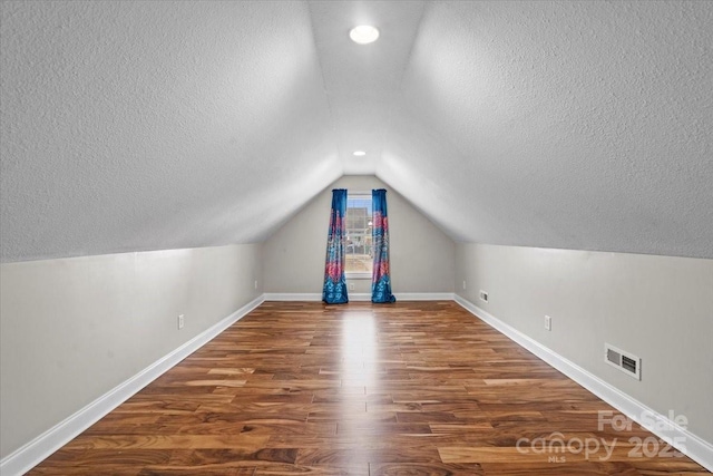 bonus room featuring a textured ceiling, lofted ceiling, and dark hardwood / wood-style floors