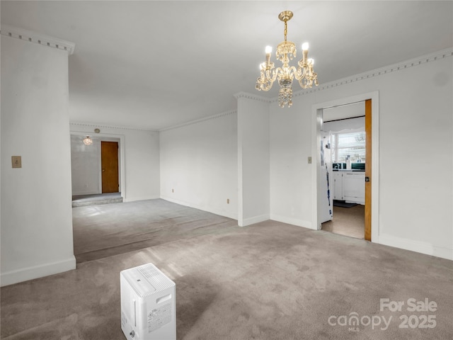 carpeted spare room with ornamental molding and a chandelier