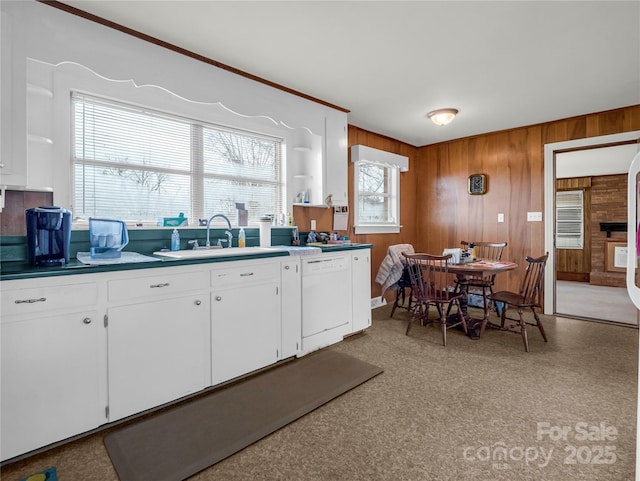 kitchen featuring white cabinetry, sink, white dishwasher, and wooden walls