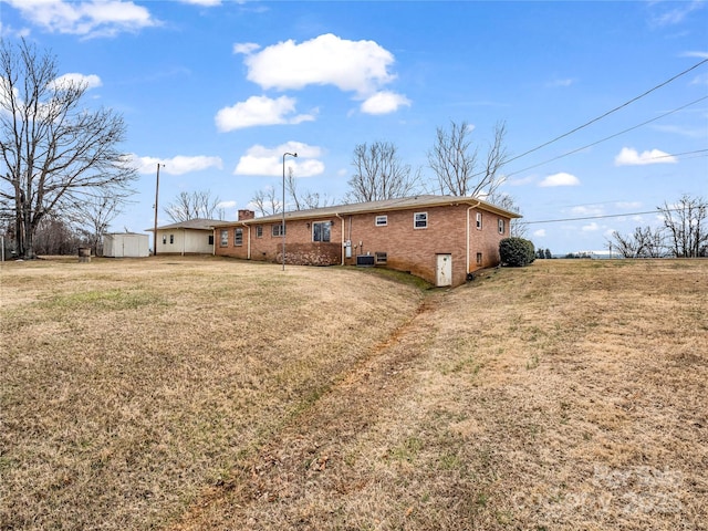 back of house featuring a storage unit and a lawn