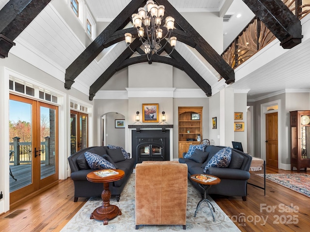 living room featuring french doors, high vaulted ceiling, hardwood / wood-style flooring, an inviting chandelier, and built in shelves