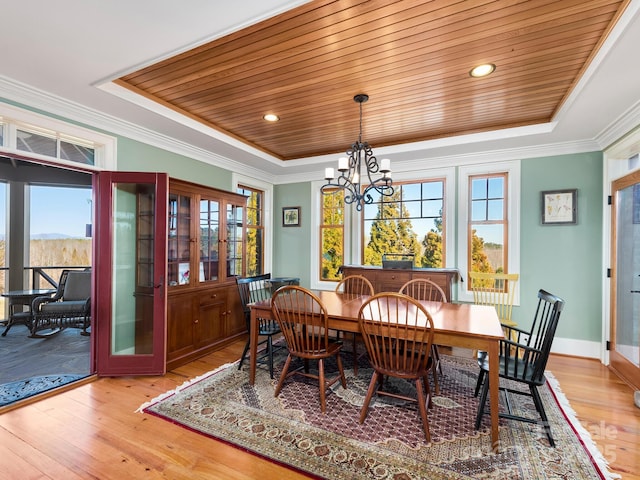 dining space with light hardwood / wood-style floors, a raised ceiling, and a wealth of natural light