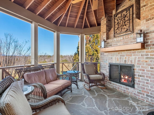 sunroom / solarium with wooden ceiling, lofted ceiling with beams, and an outdoor brick fireplace