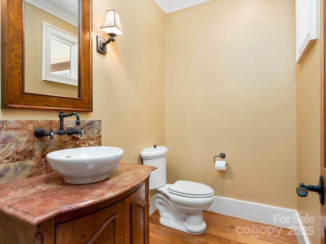 bathroom featuring toilet, vanity, ornamental molding, and hardwood / wood-style floors