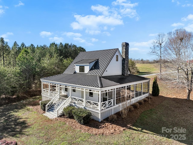 back of property featuring a porch, a yard, and a sunroom