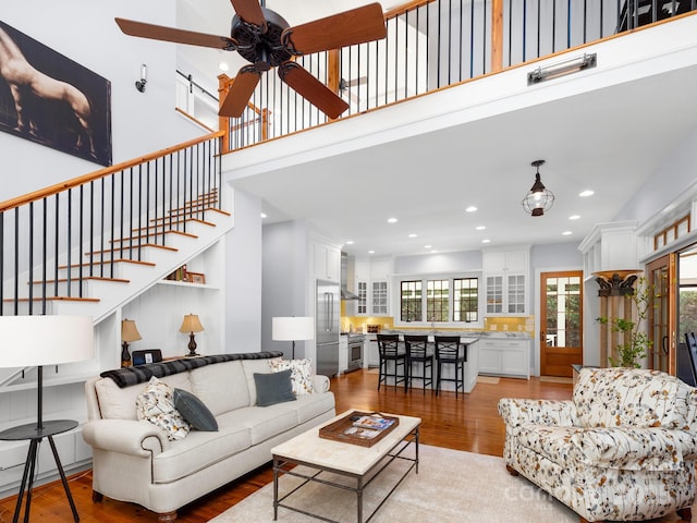 living room featuring a towering ceiling, ceiling fan, and light hardwood / wood-style floors