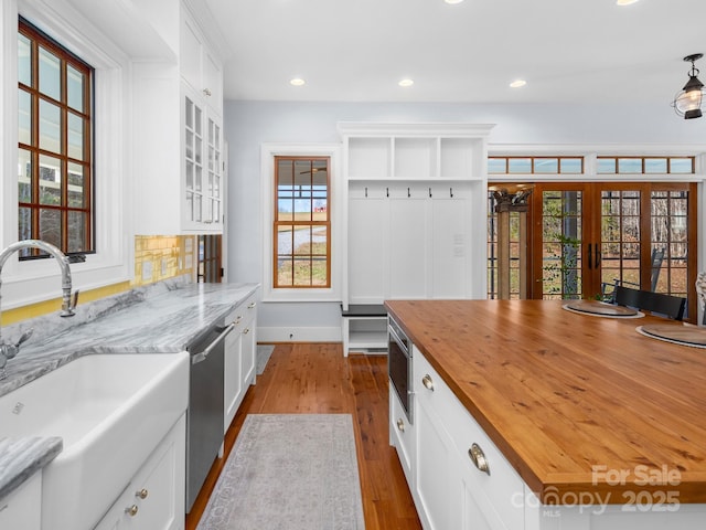 kitchen featuring dishwasher, wood counters, french doors, sink, and white cabinetry