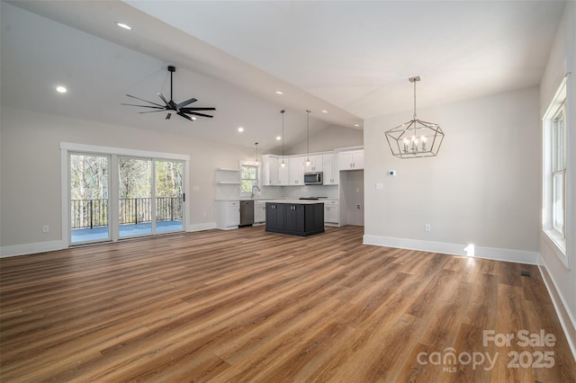 unfurnished living room featuring hardwood / wood-style floors, vaulted ceiling, and ceiling fan with notable chandelier