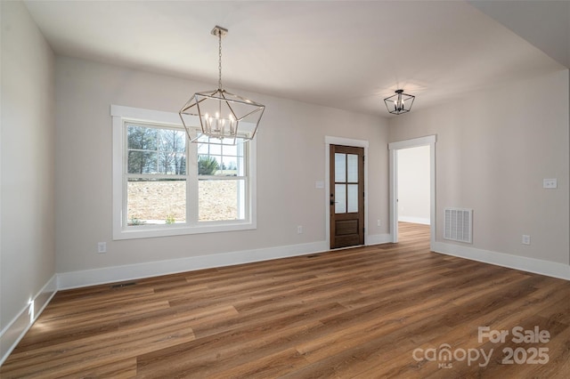 unfurnished dining area with a notable chandelier and dark hardwood / wood-style floors