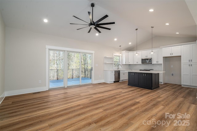 kitchen with stainless steel appliances, a kitchen island, white cabinets, and ceiling fan