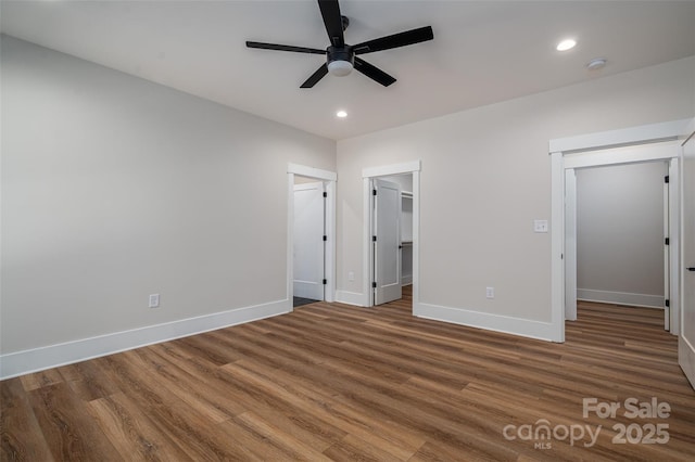 unfurnished bedroom featuring ceiling fan, a spacious closet, a closet, and hardwood / wood-style floors