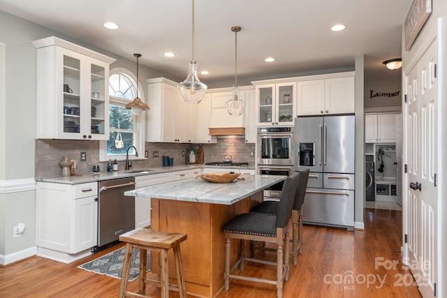 kitchen featuring stainless steel appliances, sink, dark hardwood / wood-style floors, a kitchen island, and pendant lighting