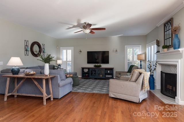 living room with a tiled fireplace, ceiling fan, and hardwood / wood-style floors