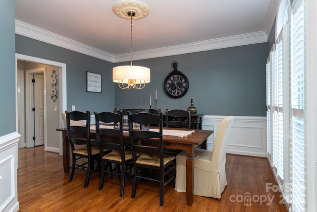 dining space with hardwood / wood-style floors, crown molding, and a notable chandelier