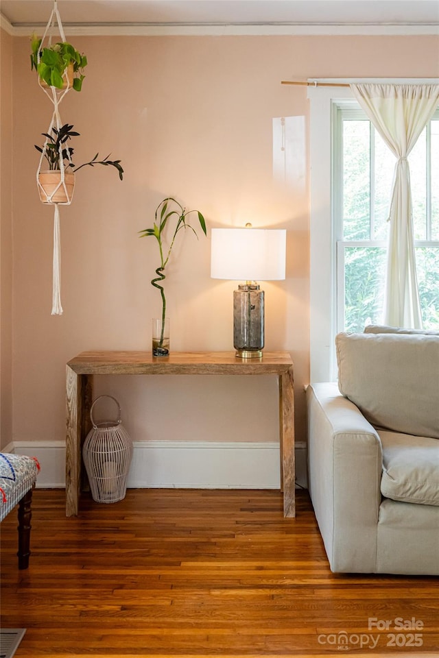 living area with hardwood / wood-style flooring and crown molding