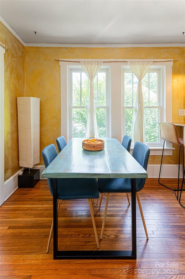 dining space with ornamental molding and hardwood / wood-style floors