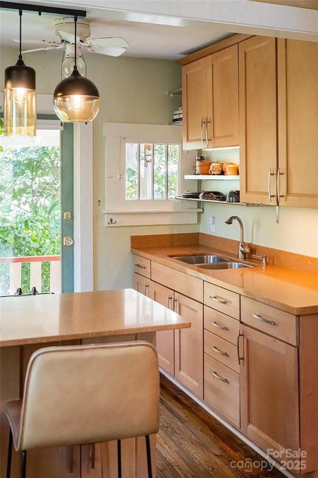 kitchen with light brown cabinetry, sink, hanging light fixtures, and dark wood-type flooring
