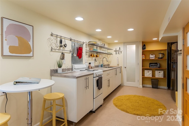 kitchen featuring electric stove, a breakfast bar, sink, and white cabinetry
