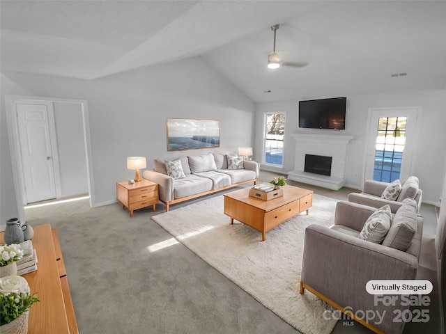 carpeted living room with ceiling fan, a fireplace, and lofted ceiling