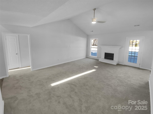 unfurnished living room featuring carpet, a wealth of natural light, a fireplace, and ceiling fan