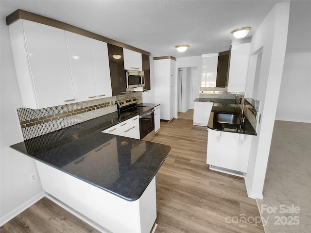 kitchen with white cabinetry, kitchen peninsula, decorative backsplash, and appliances with stainless steel finishes