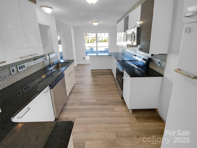 kitchen with tasteful backsplash, stainless steel appliances, sink, light hardwood / wood-style flooring, and white cabinetry