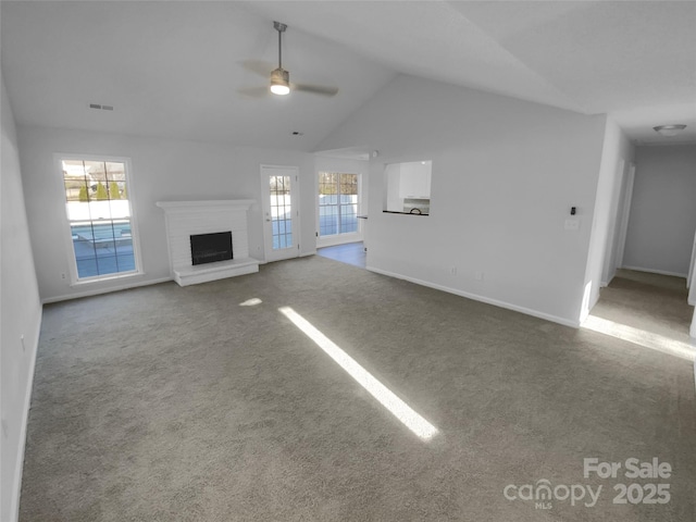 unfurnished living room with a wealth of natural light, vaulted ceiling, a brick fireplace, and ceiling fan