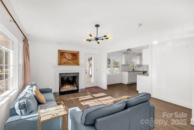 living room featuring crown molding, dark hardwood / wood-style flooring, sink, and an inviting chandelier