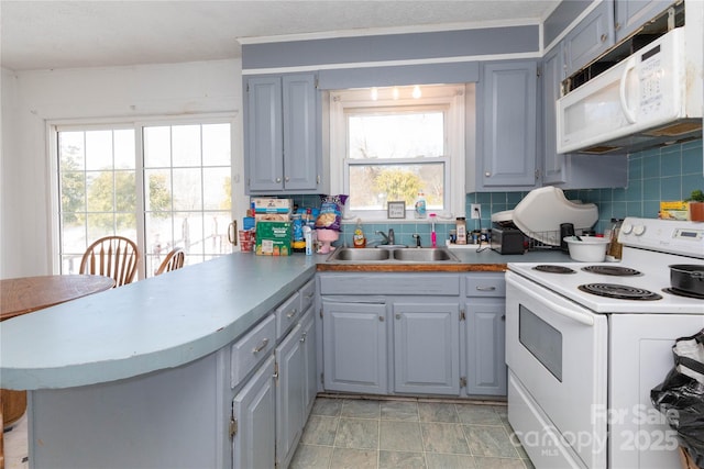 kitchen with sink, white appliances, gray cabinets, and kitchen peninsula