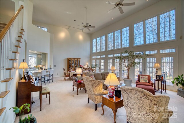 carpeted living room featuring ceiling fan, a high ceiling, and a healthy amount of sunlight