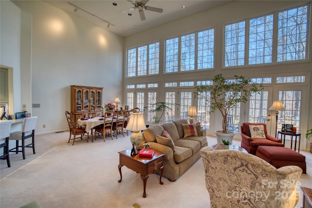 carpeted living room with ceiling fan, a high ceiling, french doors, and rail lighting