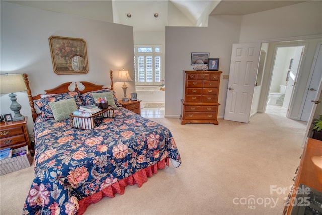 bedroom with light colored carpet, ensuite bath, and a towering ceiling