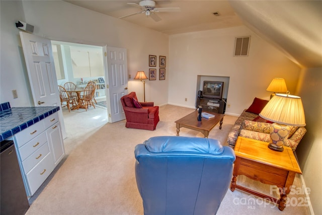 living room featuring ceiling fan, lofted ceiling, and light colored carpet