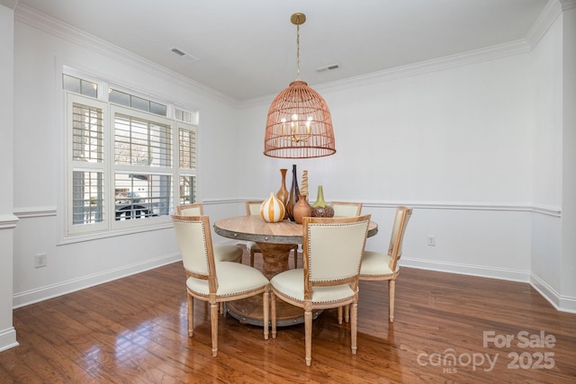 dining room with dark hardwood / wood-style flooring, crown molding, and a notable chandelier