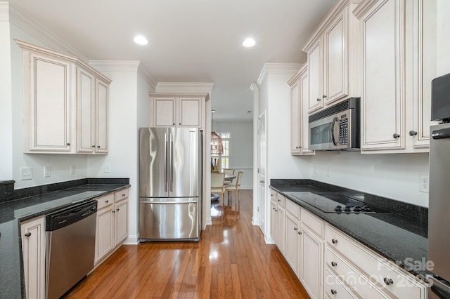 kitchen featuring dark stone counters, crown molding, stainless steel appliances, and light hardwood / wood-style flooring