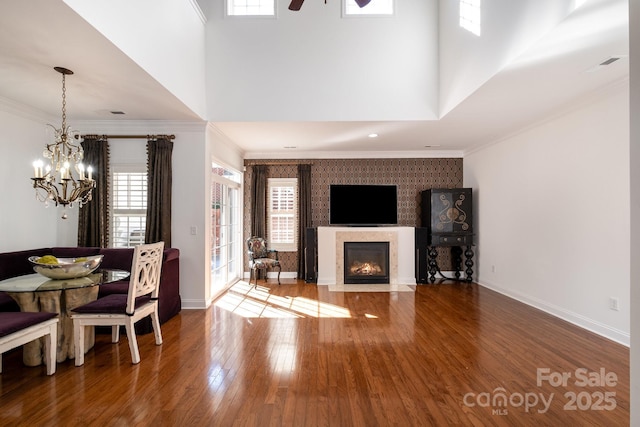 living room featuring a high ceiling, hardwood / wood-style floors, crown molding, and an inviting chandelier